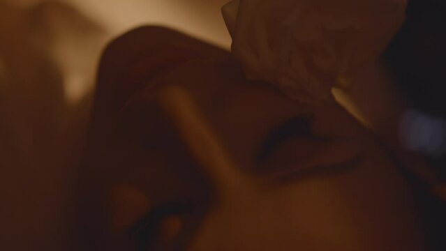 Close up of sensual woman holding white rose at her face, touches herself lying down in the car, tender slim hands, light flashes. Being in love, dreaming and waiting for a date. HQ 4k footage
