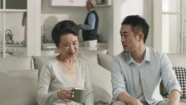 young asian adult son having a pleasant conversation with senior mother at home
