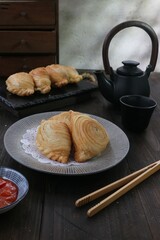 puffs filled with curried vegetables served on a wooden table against a black teaset background