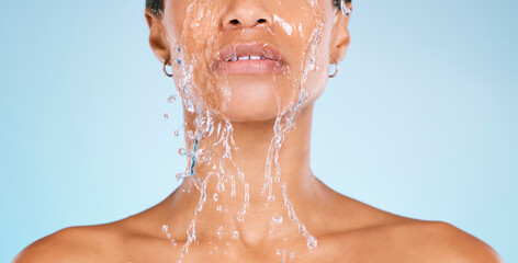 Face, water and cleaning with a black woman in studio on a blue background for hygiene or hydration. Splash, shower and bathroom with a young female washing her body for natural skincare or wellness