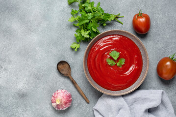Homemade tomato sauce in a bowl on a gray background. Top view, copy space.