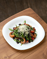 Dish with seafood. Salad with grilled shrimp, tomatoes, herbs and cheese. Healthy food. Low calorie food. Fitness menu. Vegetarian dish. Dish on white plate on wooden table. Top view. Copy space.