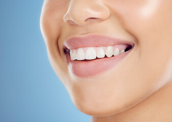 Teeth, smile and mouth of a woman for dental care isolated on a blue background in studio....