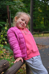 adorable portrait little girl posing pink clothes smiling outdoor green park