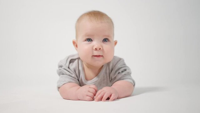 Portrait of a baby. A baby lying on his stomach in close-up against a white background, looking at the cameraman