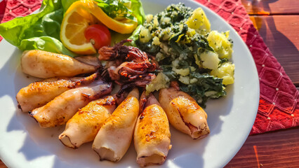 Plate of grilled squid with fresh lemon served in local restaurant in coastal village Milocer, Sveti Stefan, Budva Riviera, Adriatic Mediterranean Sea, Montenegro, Europe. Local traditional sea food