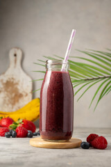 Bottle of berry smoothie in a glass. Strawberry, banana, blueberry healthy drink. Copy space.