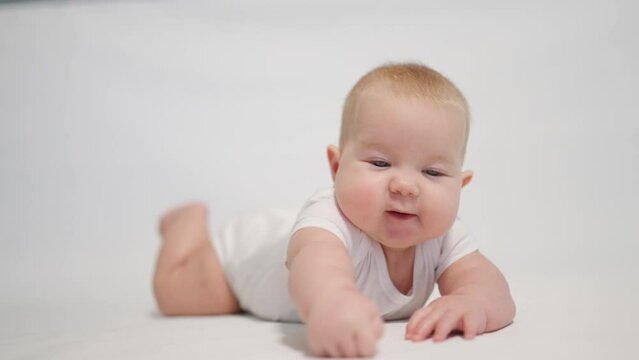 Close-up of the baby with positive emotion. on the white background, the first reflexes to uprightness