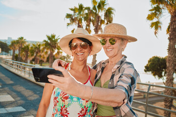 Happy friends, selfie and holiday smile in Miami with happiness from summer travel and vacation. Beach, mobile connection and online mature women by the sea with happiness on 5g for social media