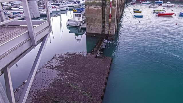 The tide going down at a port with many boats docked - time lapse