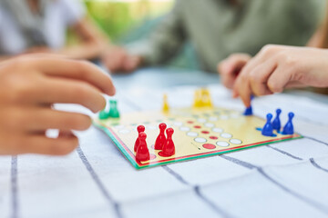 Children playing ludo with token on table in summer
