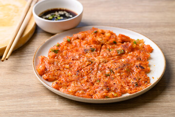 Kimchi pancake (Kimchi jeon or kimchi buchimgae) on plate eating with soy dipping sauce, Korean food