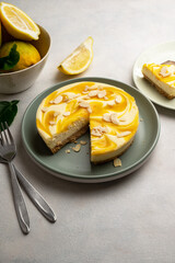 Lemon cheesecake tart or pie, with fresh lemons, neutral grey background