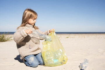 Little kid picking plastic on the beach. Recycling, save planet concept.