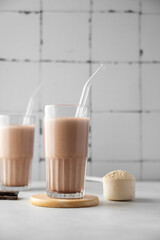 Two glasses of chocolate protein shake drink with glass straws