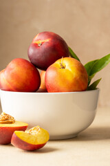 Fresh nectarine peaches fruits in a bowl. Neutral background.Summer foods.