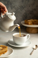 Pouring hot tea in white cup, slow living concept