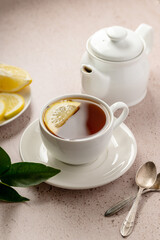 Drinking tea, white ceramic cup and tea pot with black tea and lemon slice. 
