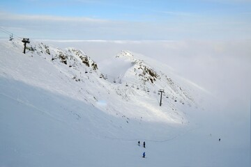 Little silhouettes of skier on slope of Kasprowy Wierch Peak in Tatras Mountains, famous place in...