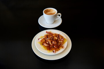 octopus dish with potatoes, olive oil and paprika, with a cup of caffe latte in the background