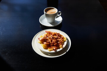 octopus dish with potatoes, olive oil and paprika, with a cup of caffe latte in the background
