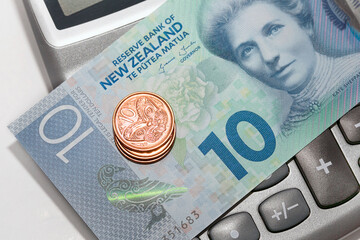New Zealand Currency - mixed coins placed on a ten dollar note over a calculator. Finance concept.