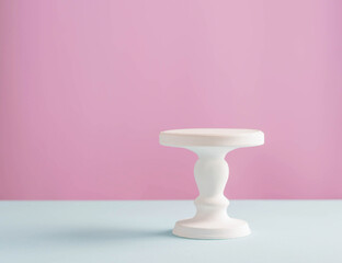 Empty white stand for a birthday cake on a pink plain background