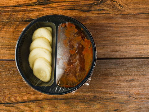 Beef Bourguignon and mash potatoes in a black plastic tray on wooden table. High quality ready meal with premium ingredients for quick lunch warm up in microwave.