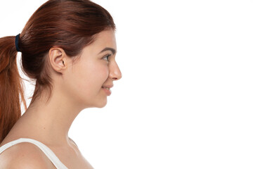 profile of a young smiling redhead woman without makeup with long hair on a white background