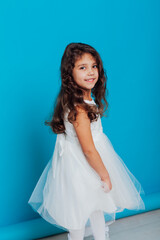 Fototapeta na wymiar little girl in a white dress on a blue background