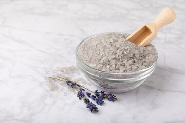 Sea salt with lavender flowers in a bowl on a white marble background. Spice. Bath salt with lavender extract and aroma. Spa procedures. Skin care concept. Beauty