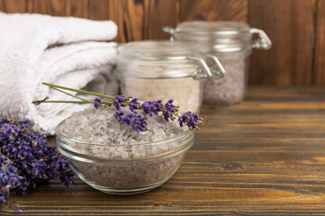 Obraz na płótnie Canvas Sea salt with lavender flowers in a bowl on a brown textural background. Bath salt with lavender extract and aroma. Beauty spa treatments. Skin care concept.