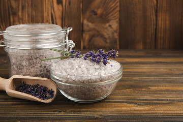 Sea salt with lavender flowers in a bowl on a brown textural background. Bath salt with lavender extract and aroma. Beauty spa treatments. Skin care concept.