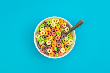 Fototapeta na wymiar Colored breakfast cereals laid out in a bowl on a blue background, top view, children's healthy breakfast.