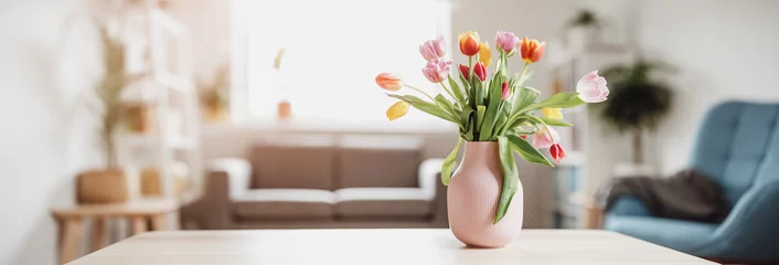 Fototapete Blumen A bunch of tulips in pink vase standing on the wooden table indoors.  © candy1812