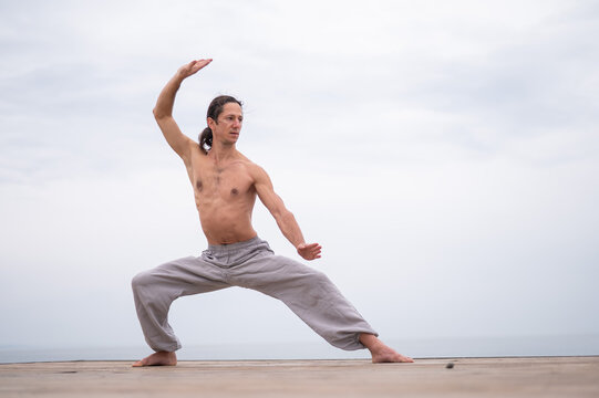 Caucasian man practices martial arts outdoors. balance and meditation.