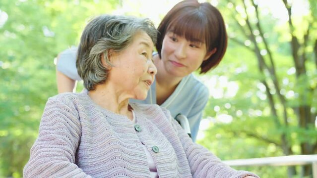 散歩に出かける車椅子のシニア女性と女性介護士