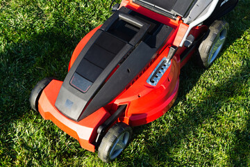 Fototapeta premium Electric Lawn mower on a green meadow. Garden equipment