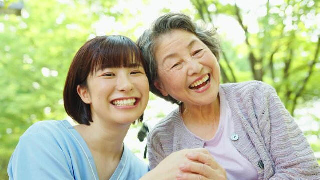公園 笑顔 車椅子に乗ったシニア女性と女性介護士
