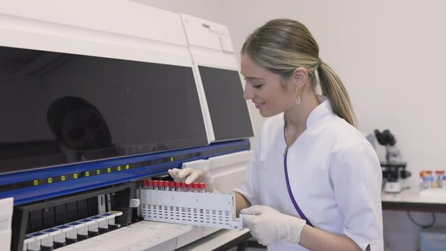 Lab tech loading samples into a chemistry analyzer. female lab tech loading specimen for coagulation test analysis