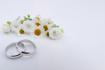 Close up of  wedding rings with small white flowers and copy space Wedding invitation background
