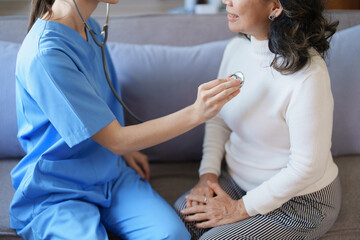 Fototapeta premium Portrait of a female doctor using a stethoscope to check the pulse of an elderly patient.