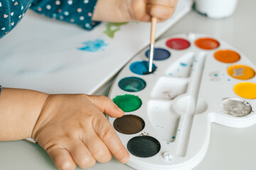 Cute little girl painting picture on home interior background