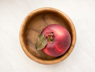 An apple in a wooden bowl.