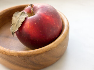 An apple in a wooden bowl.