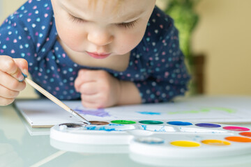 Cute little Girl painting picture on home interior background. Cute Little toddler girl drawing.