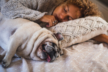 People and dog in relax sleeping indoor leisure activity at home. One female puppy pet owner asleep with her best friend forever near her. Love and health therapy. Adorable pug sleep with her owner