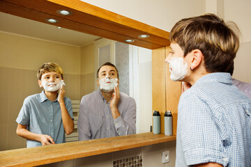 Father and the son shave in bathroom putting foam on face