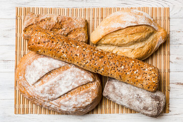 Assortment of freshly baked bread with napkin on rustic table top view. Healthy unleavened bread. French bread