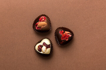 chocolate sweets in the form of a heart with fruits and nuts on a colored background. top view with space for text, holiday concept